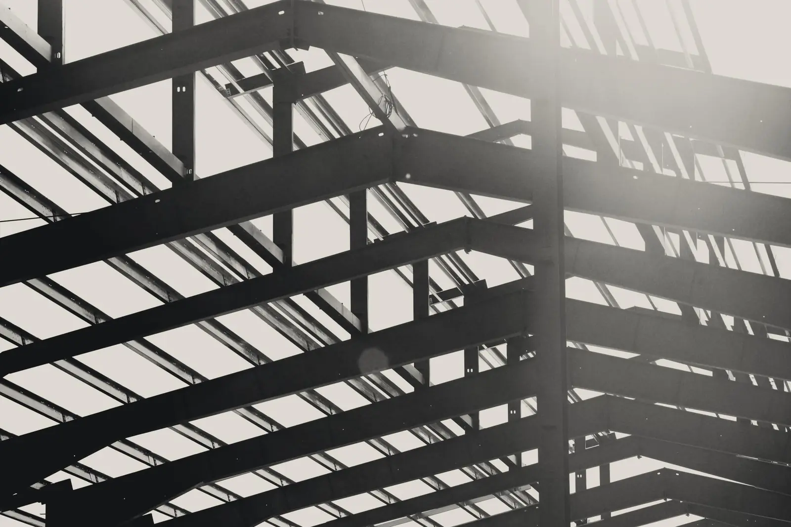 Steel roof beams of a building frame against a bright sky