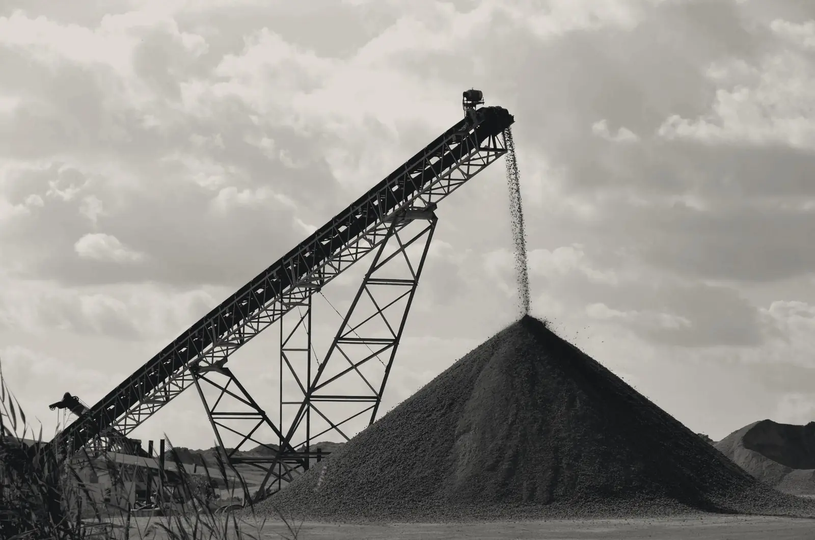 A conveyor depositing aggregate onto a conical stockpile